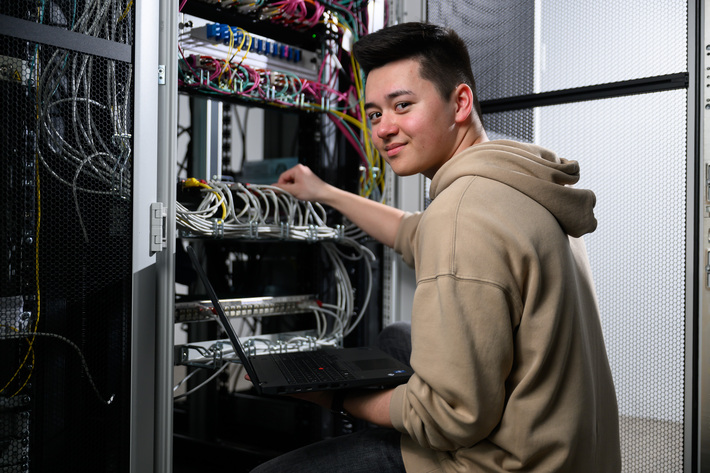 Ein Fachinformatiker kontrolliert die Kabel in einem Serverraum.