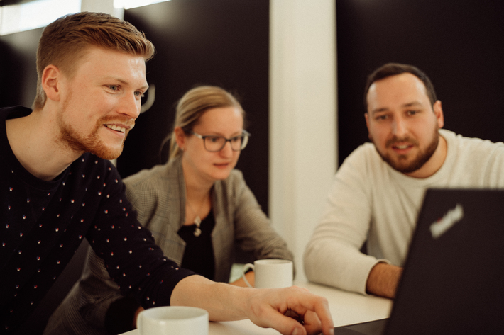 Drei Kolleg*innen aus der IT in einer lockeren Besprechung